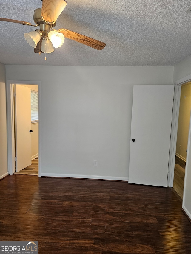 unfurnished room with ceiling fan, a textured ceiling, and dark hardwood / wood-style flooring