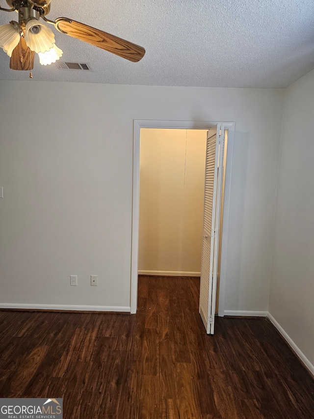 empty room featuring dark hardwood / wood-style floors, a textured ceiling, and ceiling fan