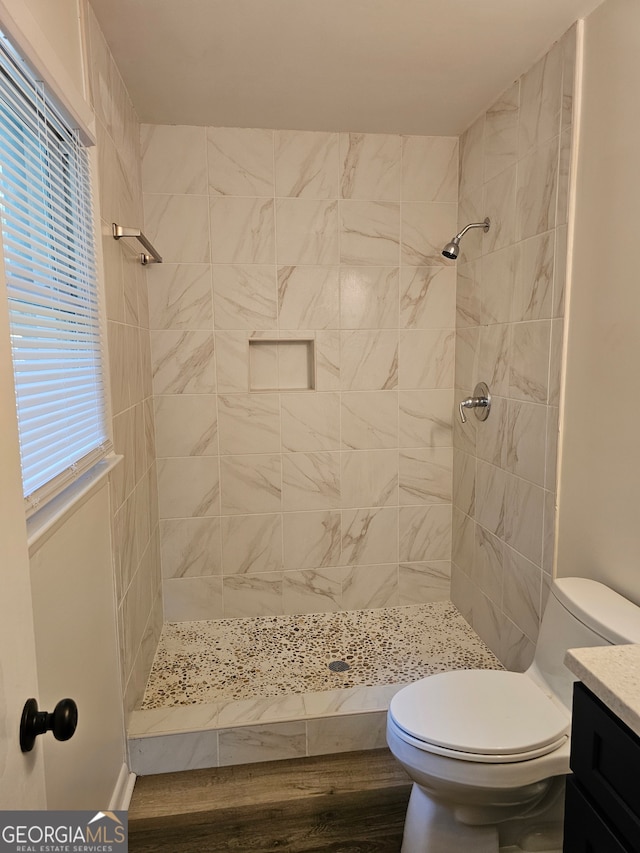 bathroom with vanity, tiled shower, and toilet