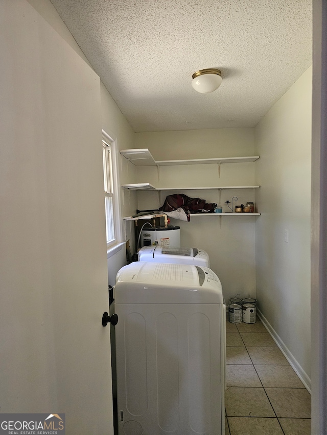 clothes washing area with a textured ceiling, separate washer and dryer, and light tile patterned floors