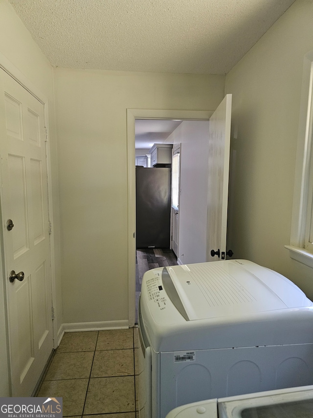 clothes washing area with washer and dryer, tile patterned floors, and a textured ceiling