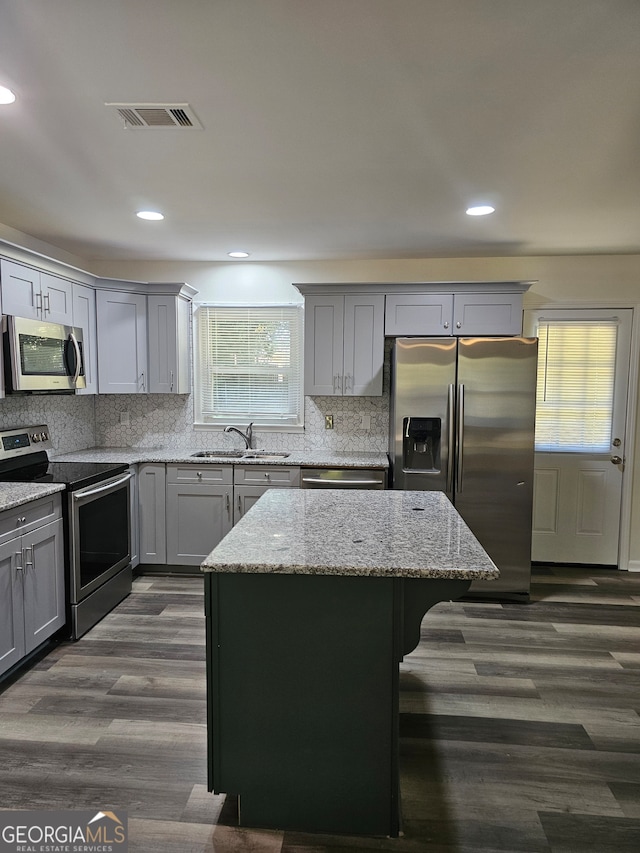 kitchen with light stone countertops, sink, a center island, and appliances with stainless steel finishes