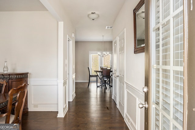 hall featuring dark wood-type flooring and an inviting chandelier