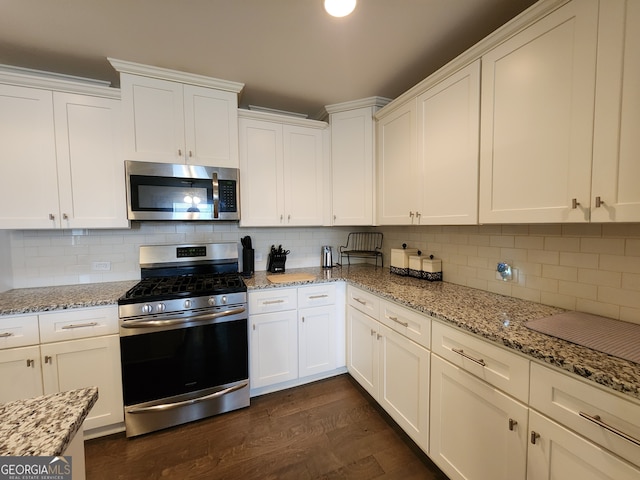 kitchen with backsplash, dark wood-type flooring, appliances with stainless steel finishes, and white cabinets