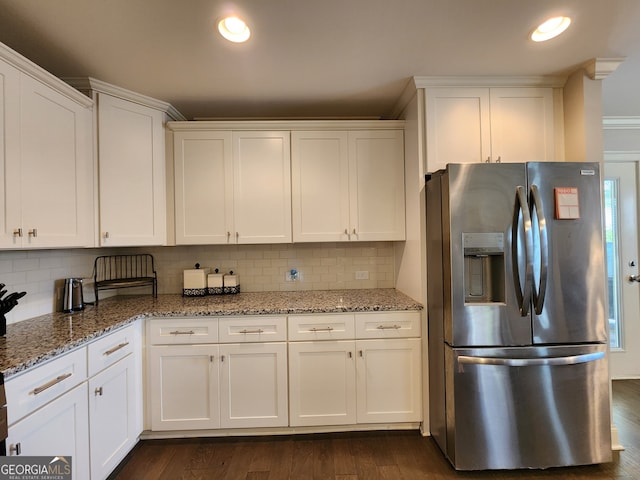 kitchen with white cabinets, light stone counters, dark hardwood / wood-style floors, and stainless steel fridge