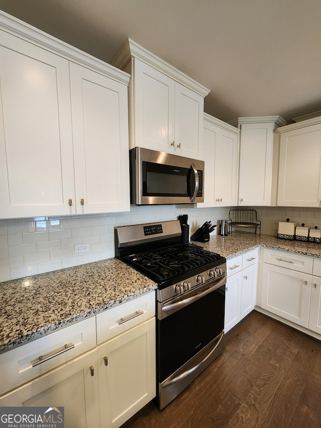 kitchen featuring decorative backsplash, appliances with stainless steel finishes, white cabinetry, dark wood-type flooring, and light stone counters