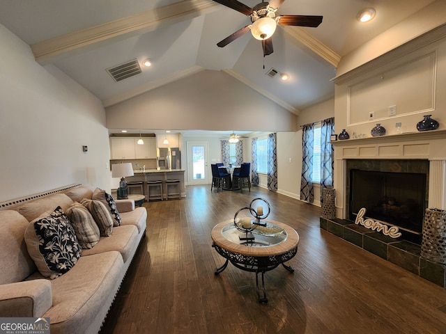 living room with beam ceiling, a tiled fireplace, dark wood-type flooring, and plenty of natural light