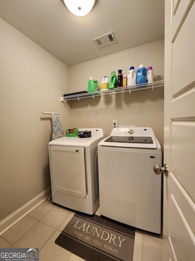 clothes washing area featuring washing machine and dryer and light tile patterned flooring