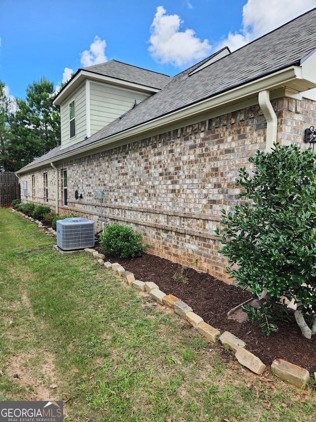 view of side of home with a lawn and central AC unit