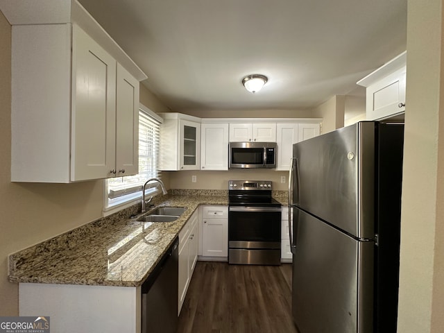 kitchen with light stone counters, appliances with stainless steel finishes, white cabinetry, dark hardwood / wood-style floors, and sink