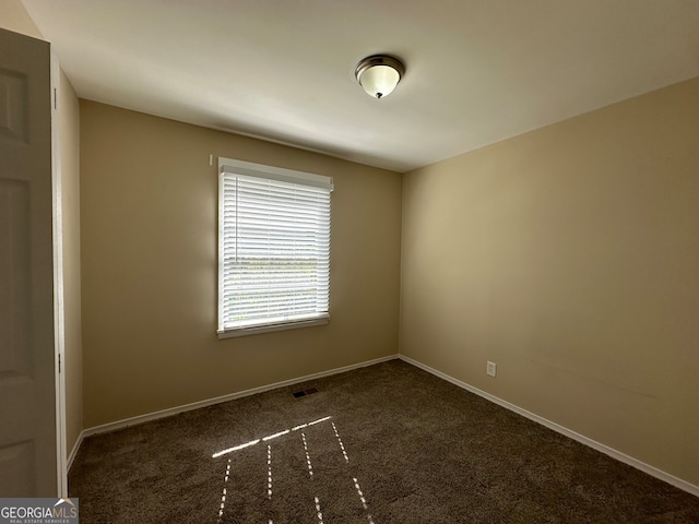 unfurnished room with dark colored carpet