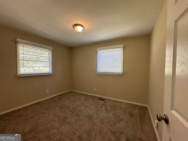 spare room with dark carpet