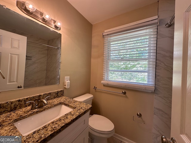 bathroom featuring vanity, toilet, and tiled shower