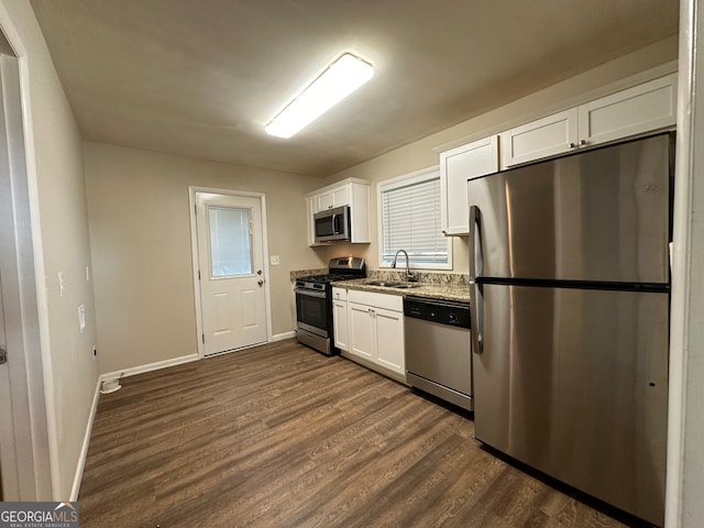 kitchen featuring white cabinets, dark stone countertops, dark hardwood / wood-style floors, sink, and stainless steel appliances