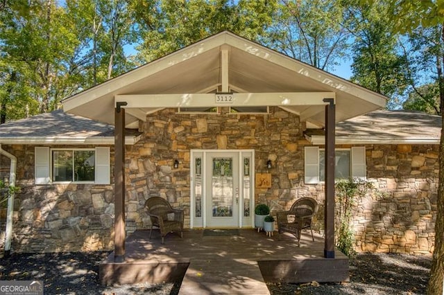 property entrance featuring roof with shingles and stone siding