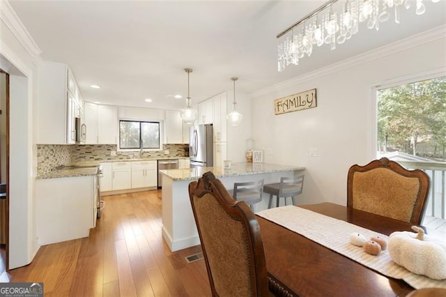 dining space with crown molding and light wood-type flooring