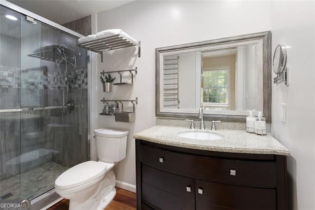 full bath featuring a shower stall, toilet, vanity, and wood finished floors