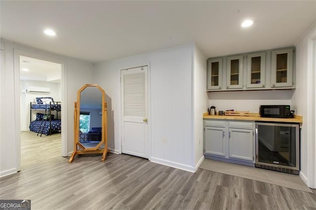 bar with a wall mounted AC, hardwood / wood-style flooring, beverage cooler, and wood counters