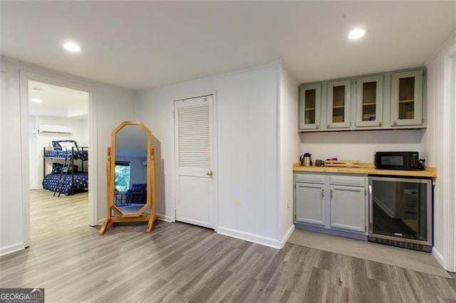 bar featuring beverage cooler, black microwave, bar area, baseboards, and light wood-style flooring