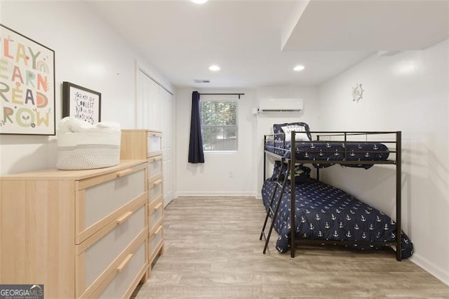 bedroom with light wood finished floors, baseboards, a wall mounted AC, and recessed lighting