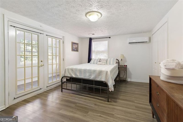 bedroom with french doors, a textured ceiling, access to outside, an AC wall unit, and dark hardwood / wood-style floors