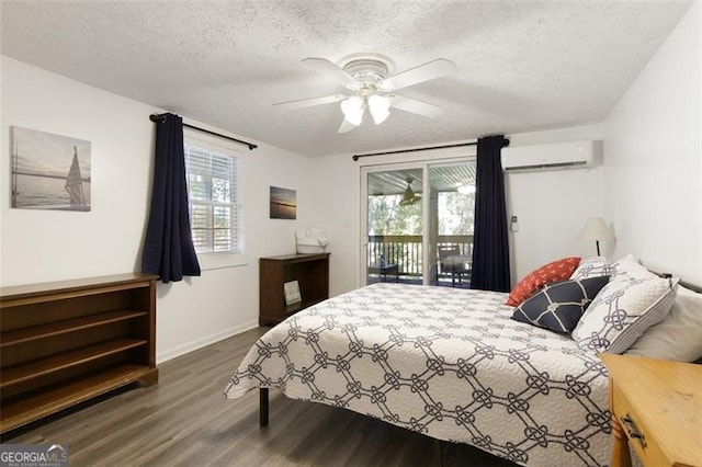 bedroom with a wall mounted air conditioner, dark wood-type flooring, a textured ceiling, and access to exterior
