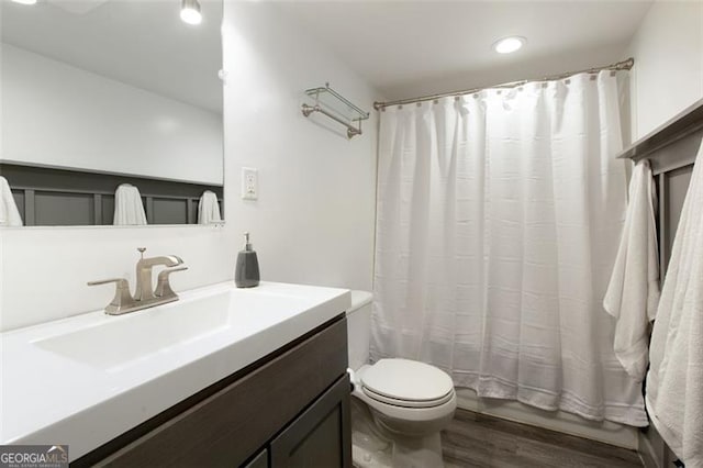 bathroom featuring shower / bath combo, toilet, vanity, and wood finished floors
