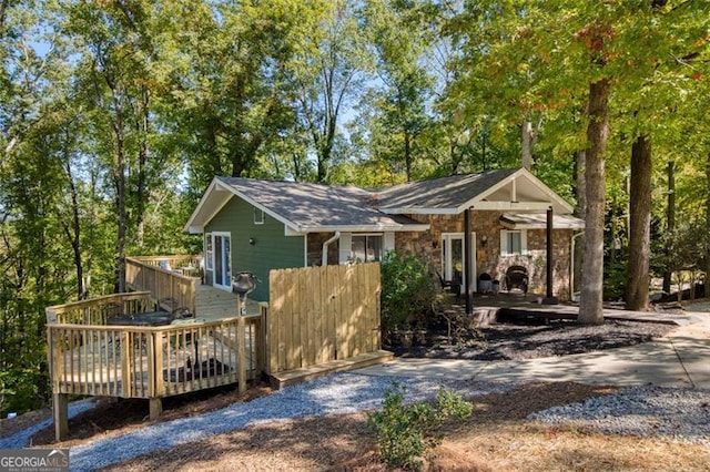 back of house with stone siding and a deck
