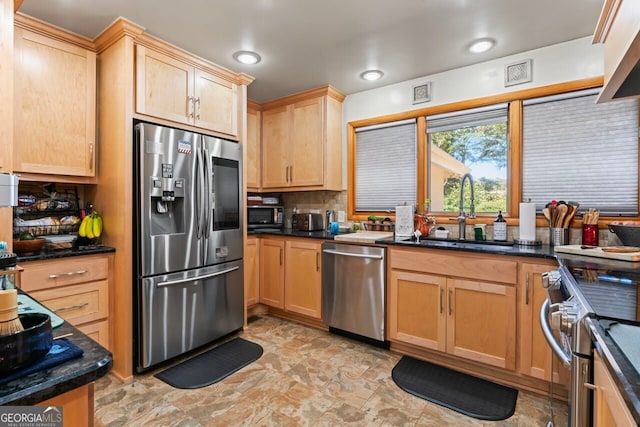 kitchen featuring sink, stainless steel appliances, backsplash, and dark stone countertops