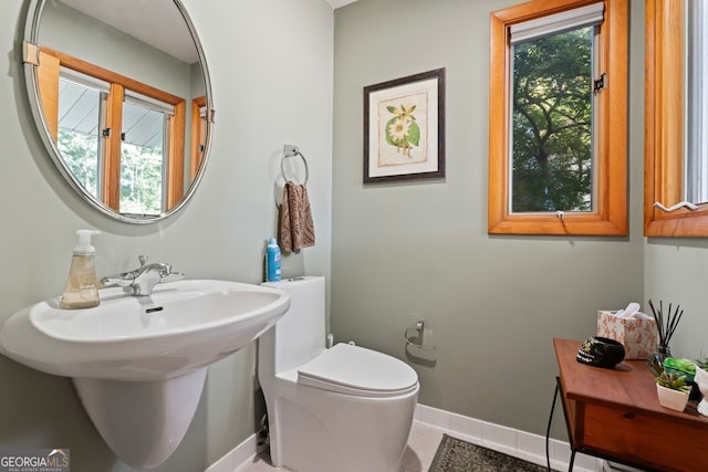 bathroom with toilet, plenty of natural light, and tile patterned flooring