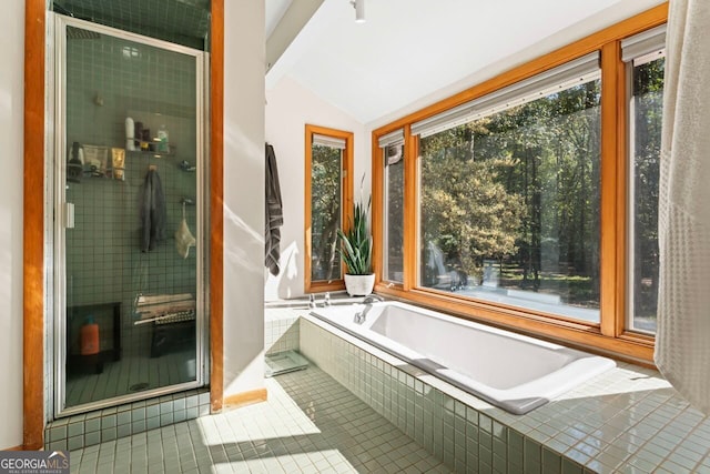 bathroom with tile patterned floors, vaulted ceiling, and tiled tub