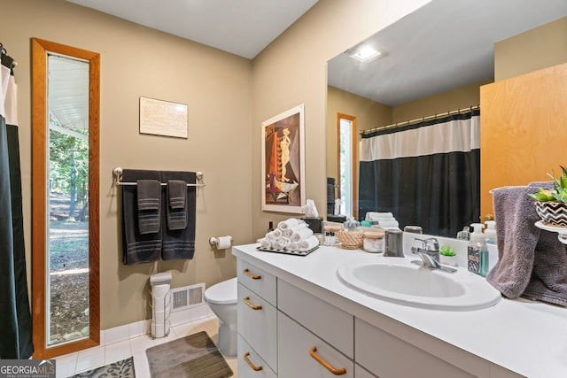 bathroom with toilet, vanity, and tile patterned floors