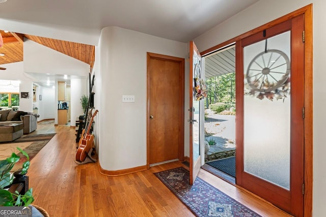 foyer entrance featuring vaulted ceiling with beams, light hardwood / wood-style flooring, and french doors