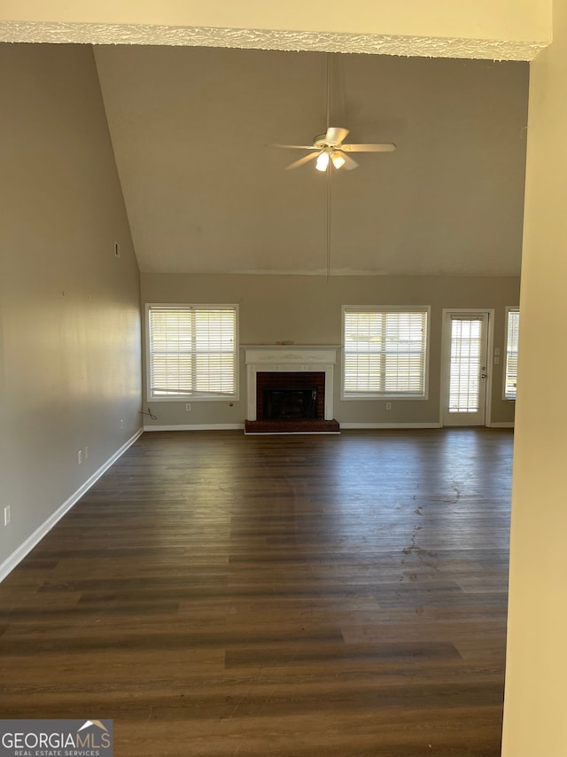 unfurnished living room featuring ceiling fan, high vaulted ceiling, a brick fireplace, and dark hardwood / wood-style floors