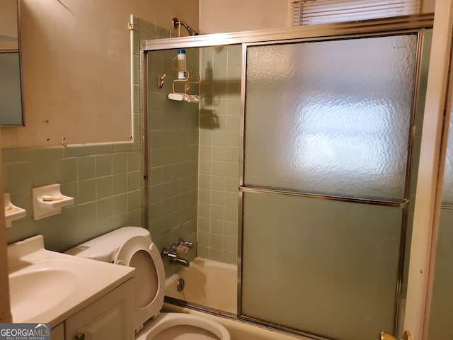 full bathroom with toilet, combined bath / shower with glass door, vanity, and tile walls