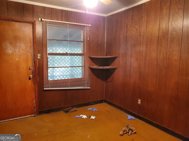 unfurnished room featuring crown molding, wooden walls, and ceiling fan