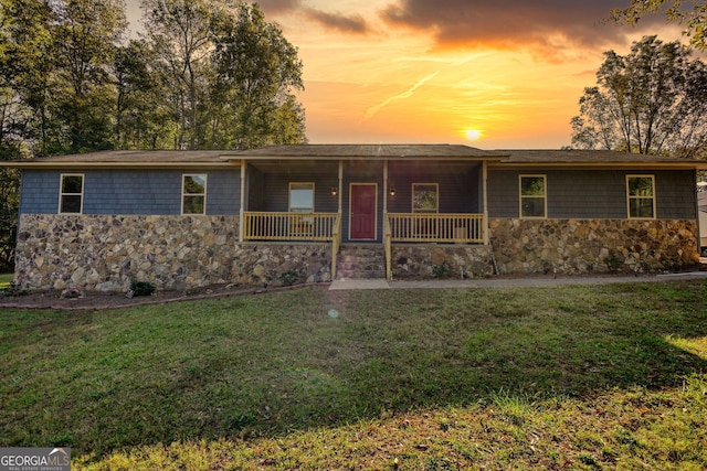 ranch-style home with covered porch and a yard