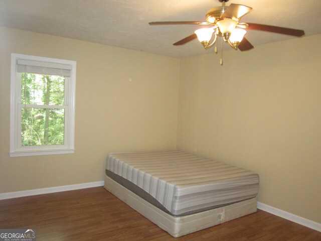 unfurnished bedroom with ceiling fan and dark hardwood / wood-style flooring