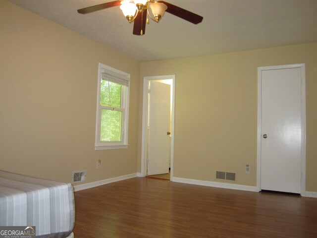 unfurnished bedroom with dark wood-type flooring and ceiling fan