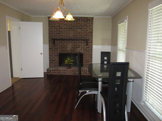 dining room featuring crown molding, dark hardwood / wood-style floors, a textured ceiling, and a fireplace