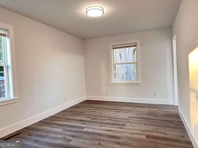 spare room featuring a healthy amount of sunlight and dark hardwood / wood-style flooring