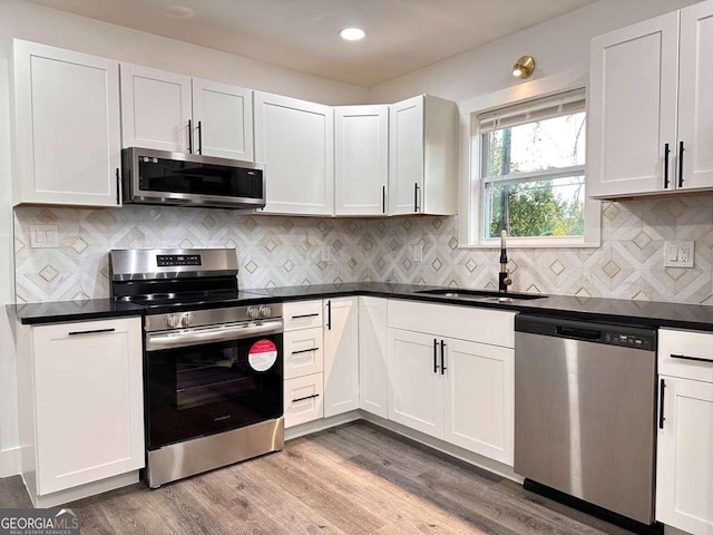 kitchen featuring sink, white cabinets, stainless steel appliances, and light wood-type flooring