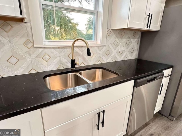 kitchen with white cabinets, dark stone countertops, dishwasher, light hardwood / wood-style floors, and sink