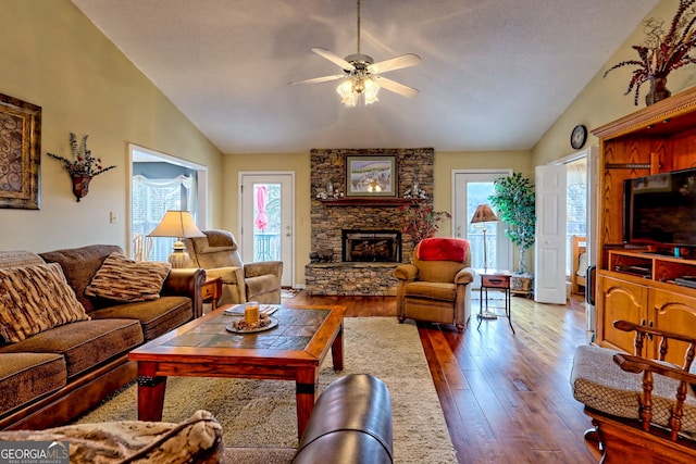 living room with lofted ceiling, hardwood / wood-style flooring, a fireplace, and ceiling fan