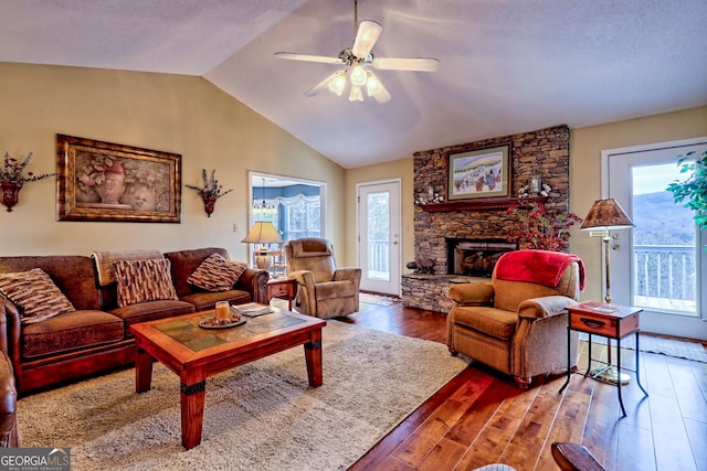 living room featuring dark hardwood / wood-style flooring, a fireplace, vaulted ceiling, and ceiling fan