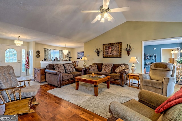 living room featuring hardwood / wood-style flooring, ceiling fan with notable chandelier, and vaulted ceiling