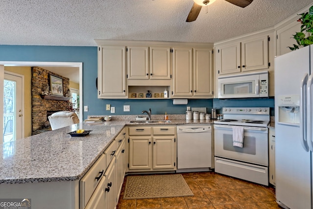 kitchen featuring light stone countertops, sink, white appliances, and kitchen peninsula