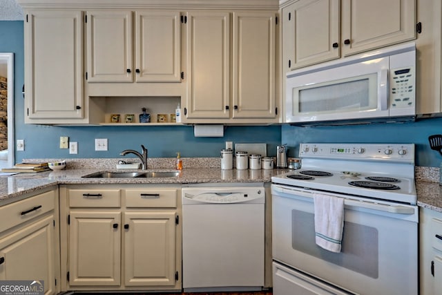 kitchen with sink, light stone counters, and white appliances