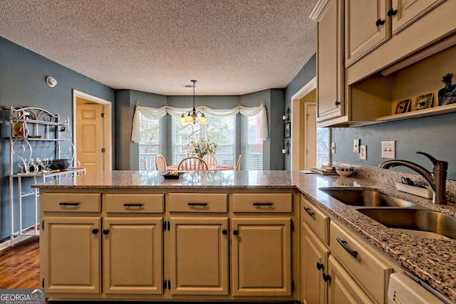 kitchen with sink, light stone counters, decorative light fixtures, stainless steel dishwasher, and kitchen peninsula