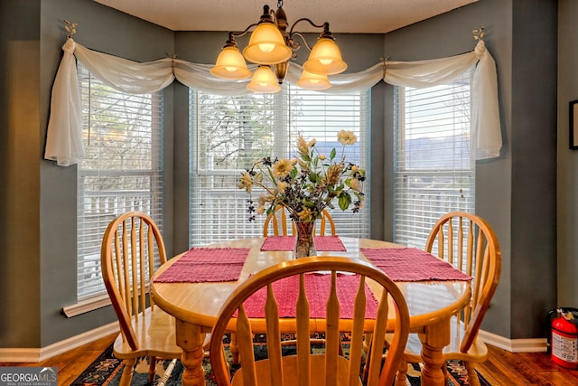 dining area with hardwood / wood-style flooring, plenty of natural light, and a notable chandelier